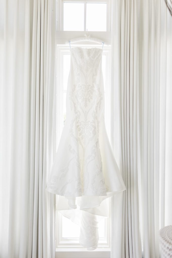 trumpet style wedding gown hanging in front of window