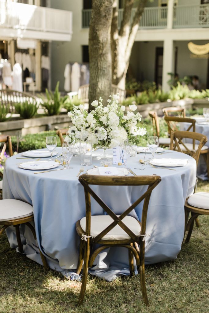 Blue wedding tables with wood chairs and white flower centrepieces 