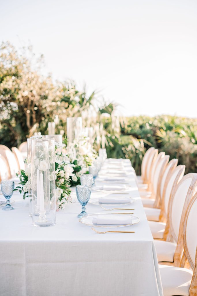 Outdoor wedding reception table with flowers, candles & wood chairs