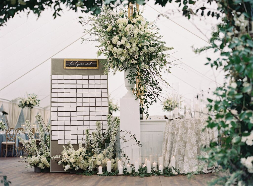 Seating chart with flowers at tented wedding reception