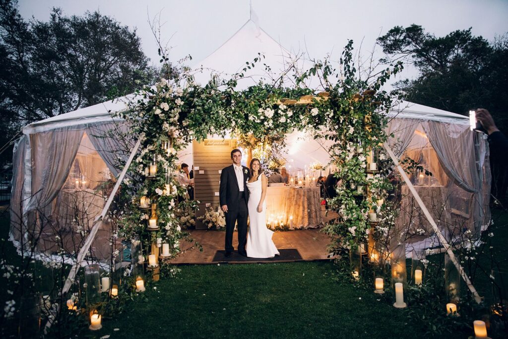 Bride and groom in front of tented wedding reception at night