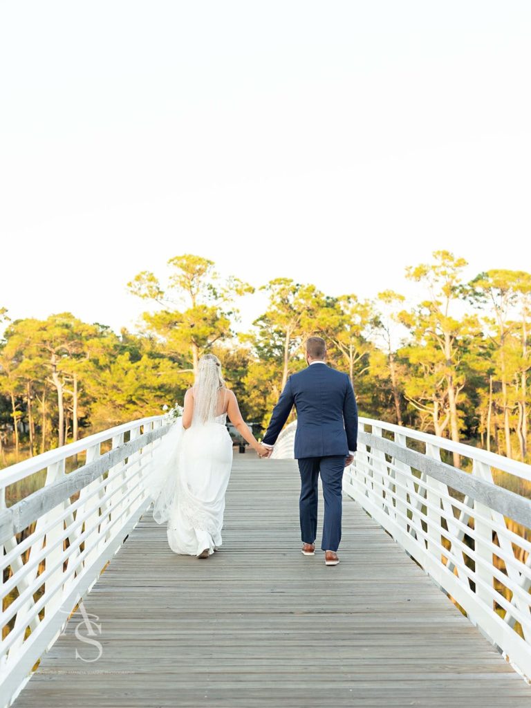 Florida bride and groom holding hands on a bridge