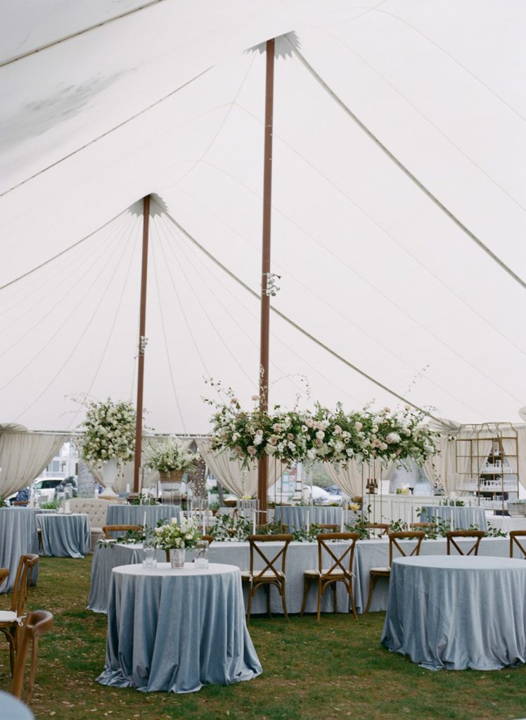 wedding reception in tent with blue tables and wood chairs