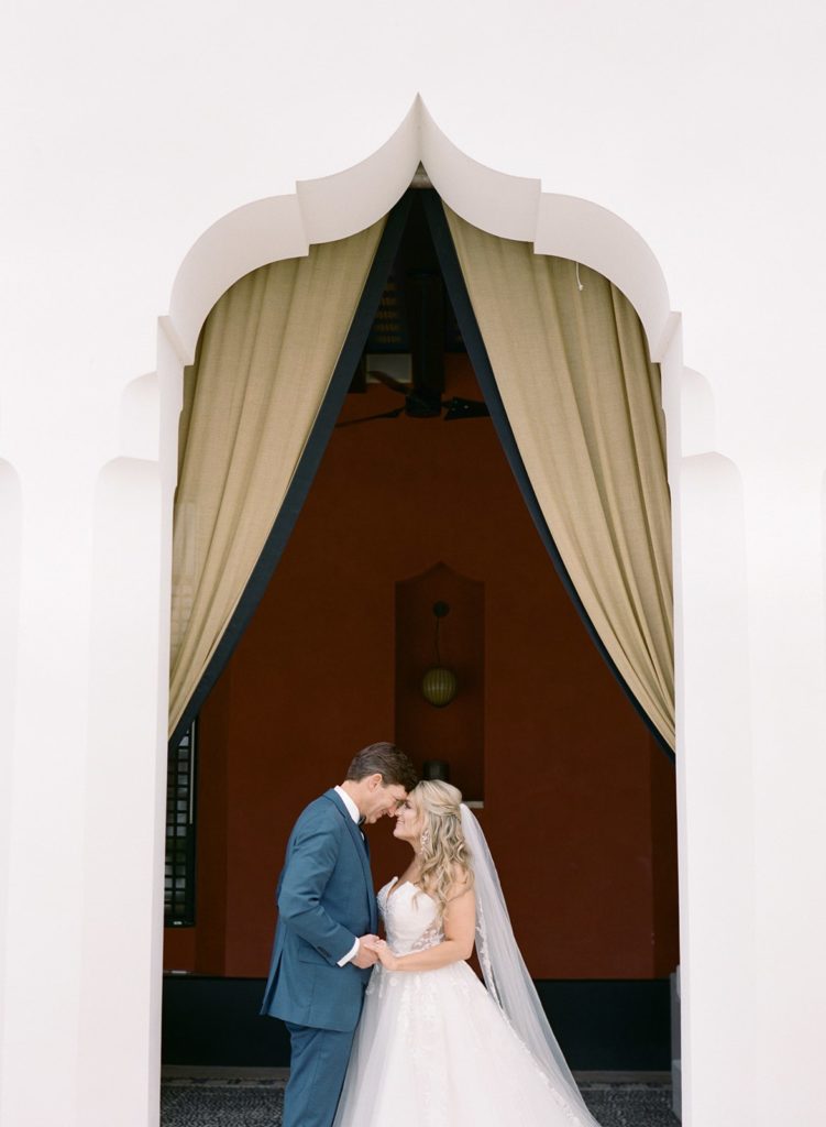 Bride and groom holding hands under doorway arch