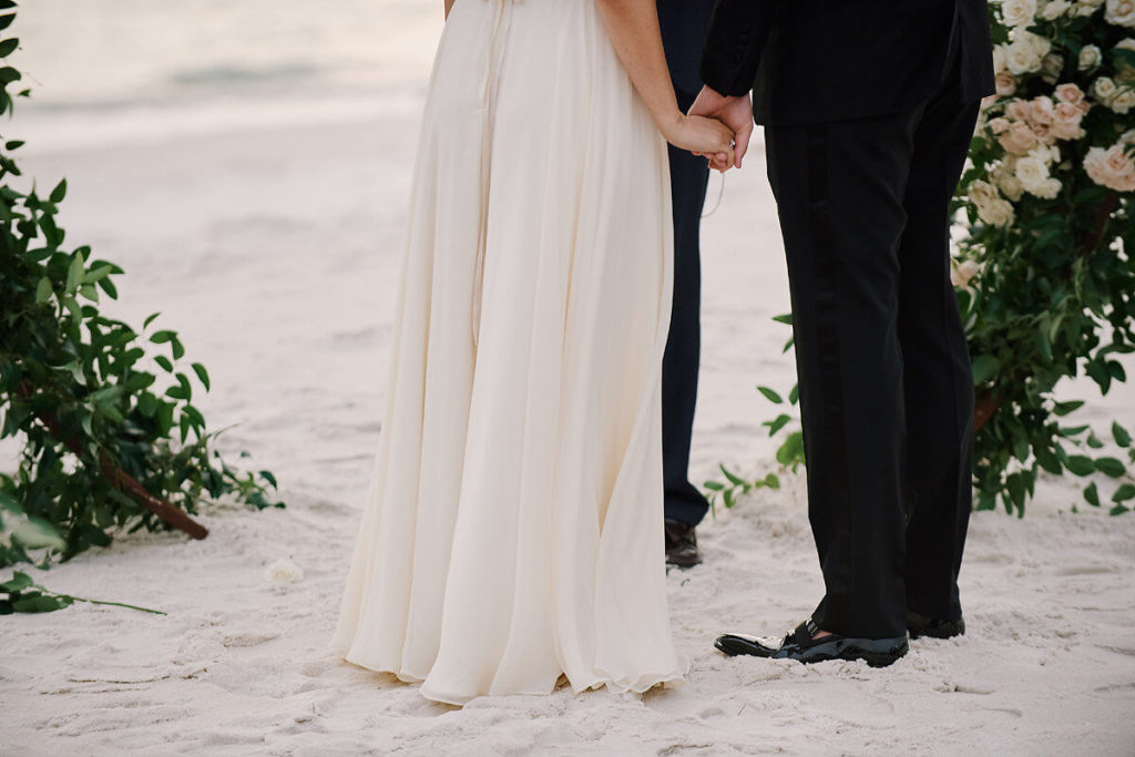 bride and groom holding hands at beach wedding ceremony