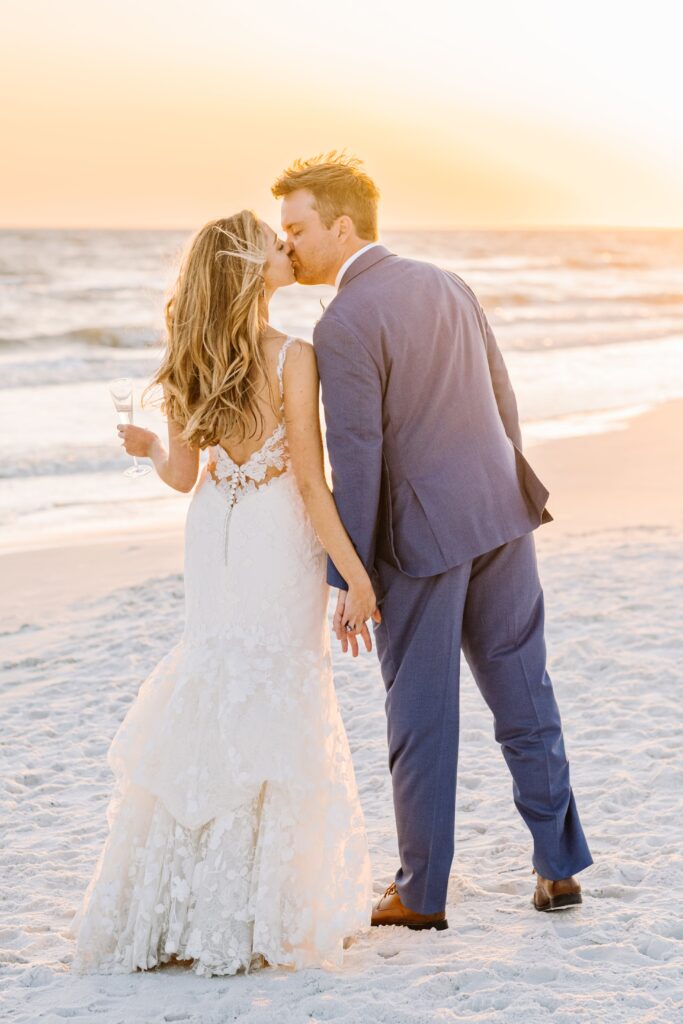 Bride and groom kissing during sunset photo on the beach